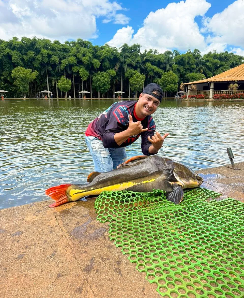 Pessoa exibindo peixe junto ao lago Pessoa exibindo peixe junto ao lago